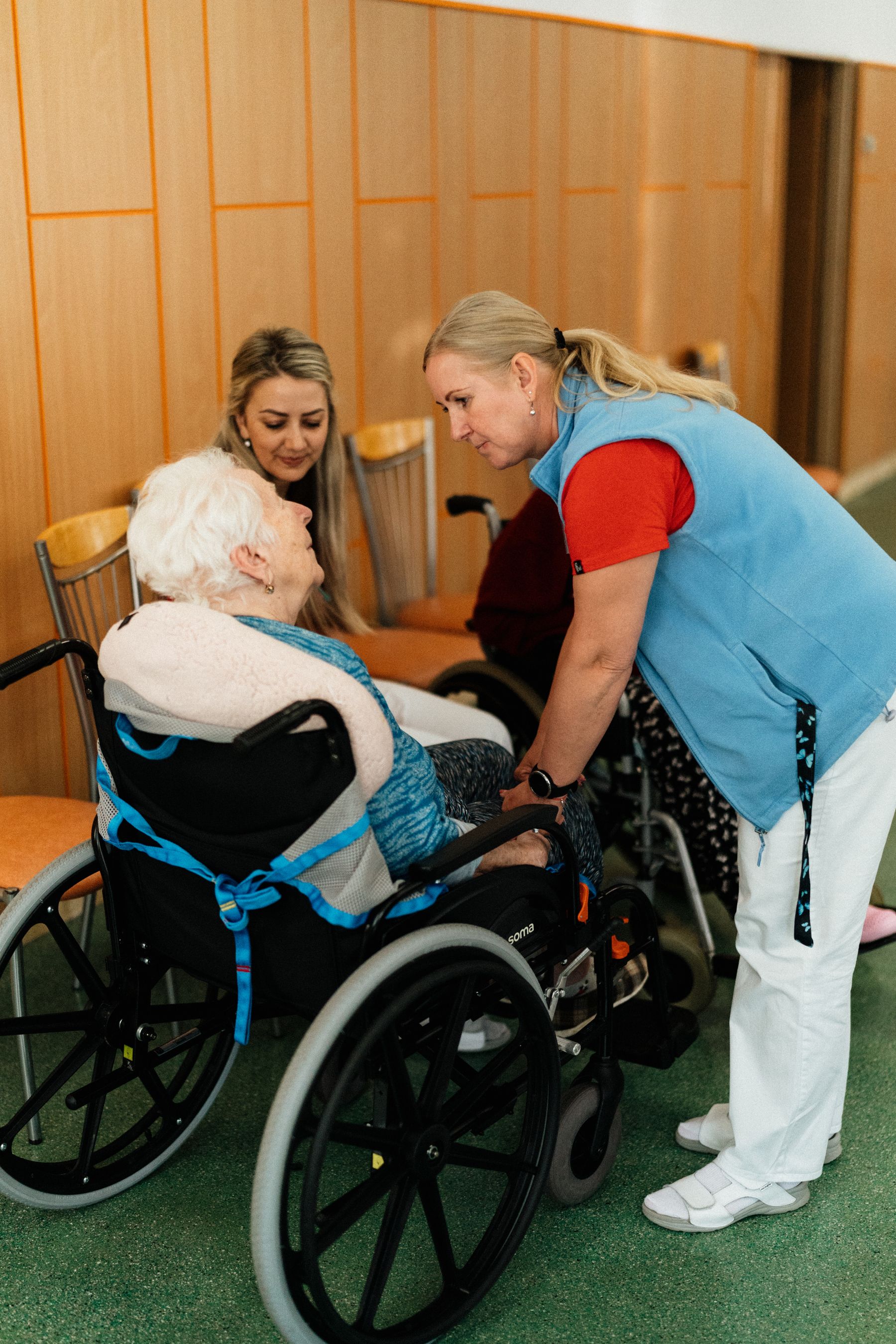 A nurse leaning in to talk with an elderly woman in a wheelchair